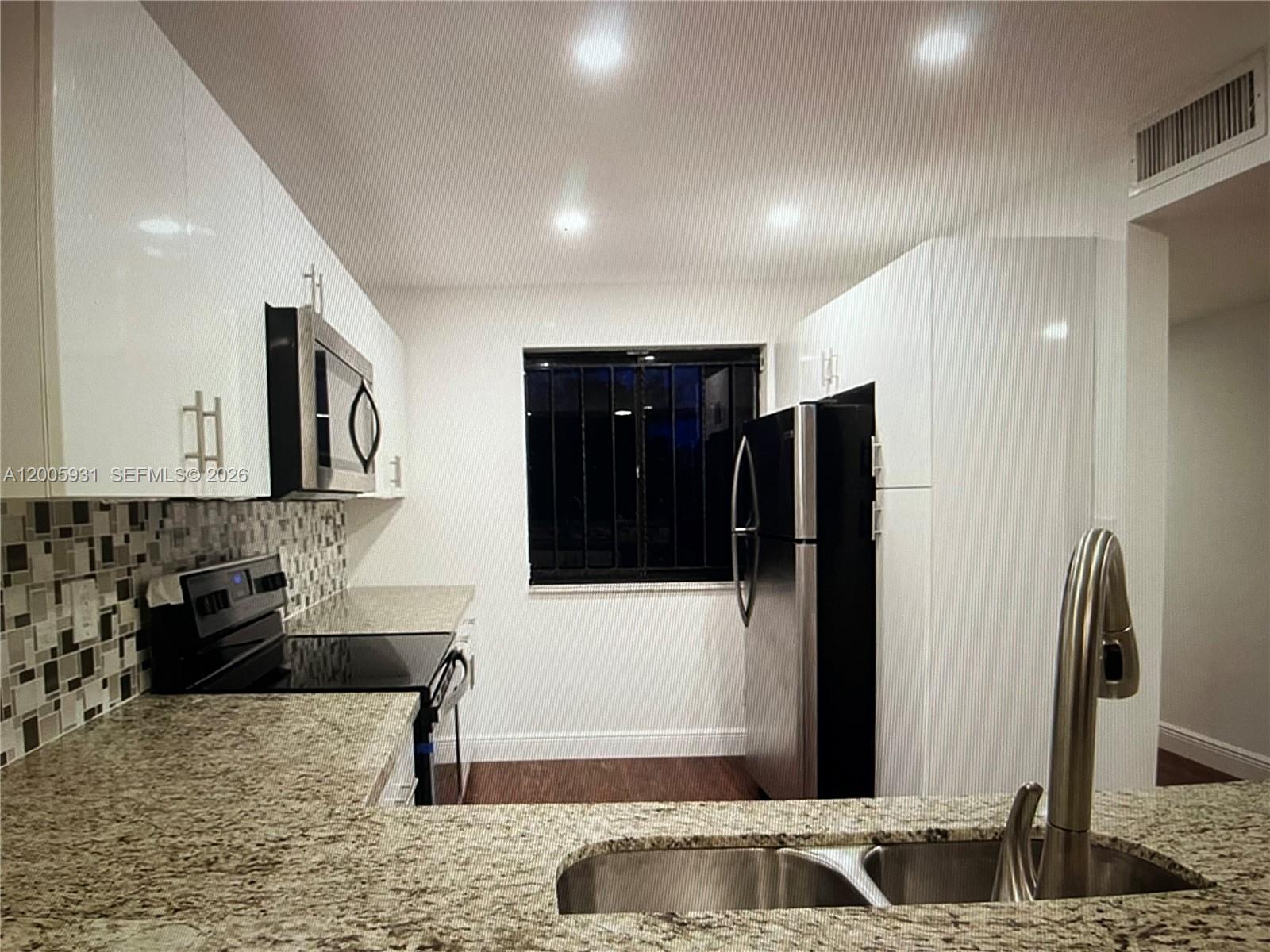 A kitchen features white cabinets, granite countertops, stainless steel appliances, and a tiled backsplash — 201 Lakeview Drive # 204, Weston FL 33326, WESTON, FL
