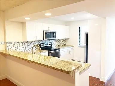 A kitchen features white cabinets, a granite countertop, and a tiled backsplash — 201 Lakeview Drive # 204, Weston FL 33326, WESTON, FL