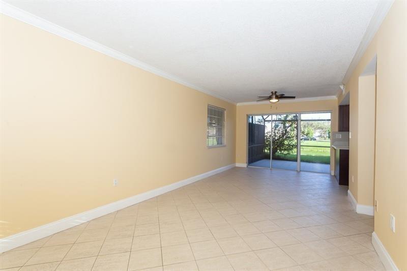 An empty living area with beige walls, tile flooring, a ceiling fan, and sliding glass doors — 5200 Lake Loop Road, Cooper City FL 33330, COOPER CITY, FL