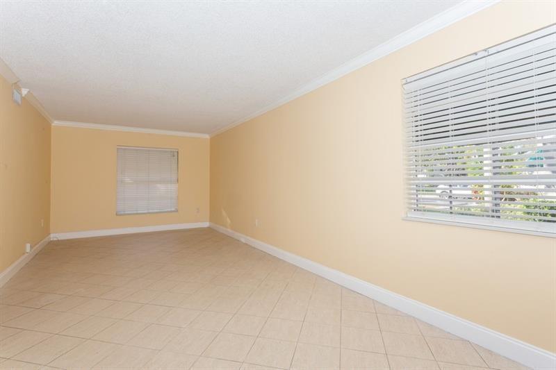 An empty room features light-colored tile flooring, pale yellow walls, and two windows with blinds — 5200 Lake Loop Road, Cooper City FL 33330, COOPER CITY, FL