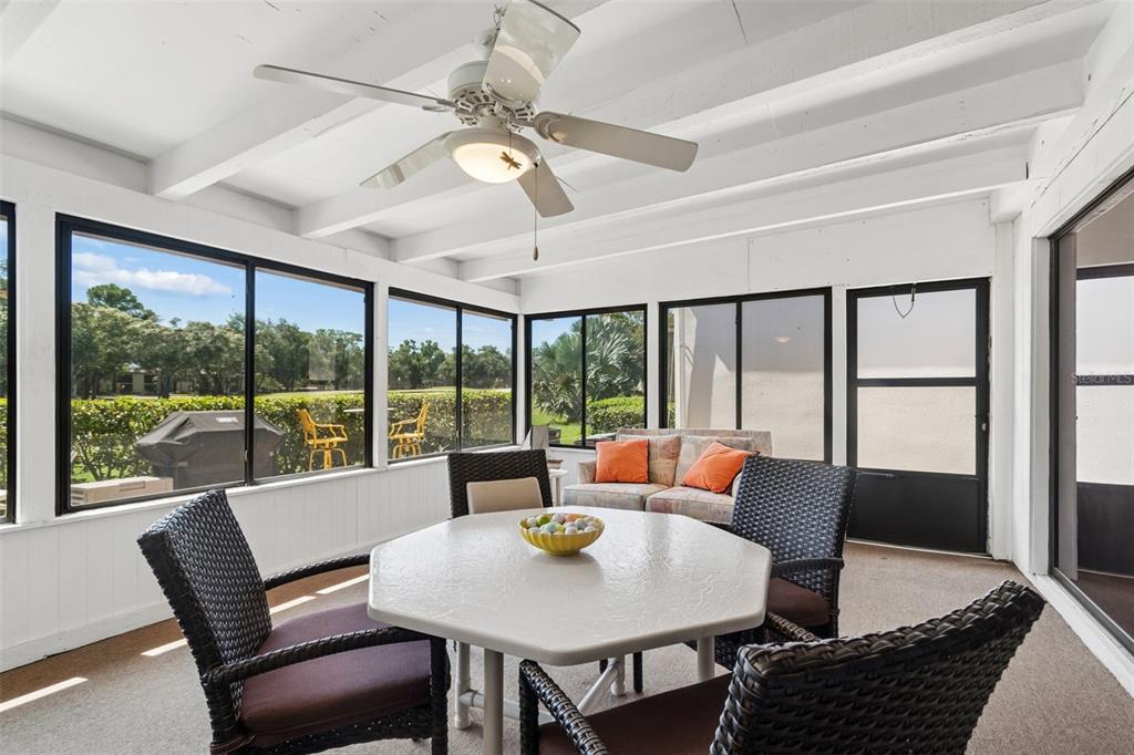 A sunroom features a white hexagonal table, wicker chairs, a ceiling fan, and large windows — 100 LISA LANE, OLDSMAR, FL