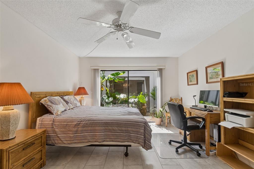 A bedroom features a bed, a desk, a ceiling fan, and a sliding glass door — 100 LISA LANE, OLDSMAR, FL