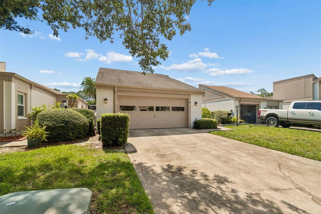A beige single-story house with a two-car garage and a concrete driveway — 100 LISA LANE, OLDSMAR, FL