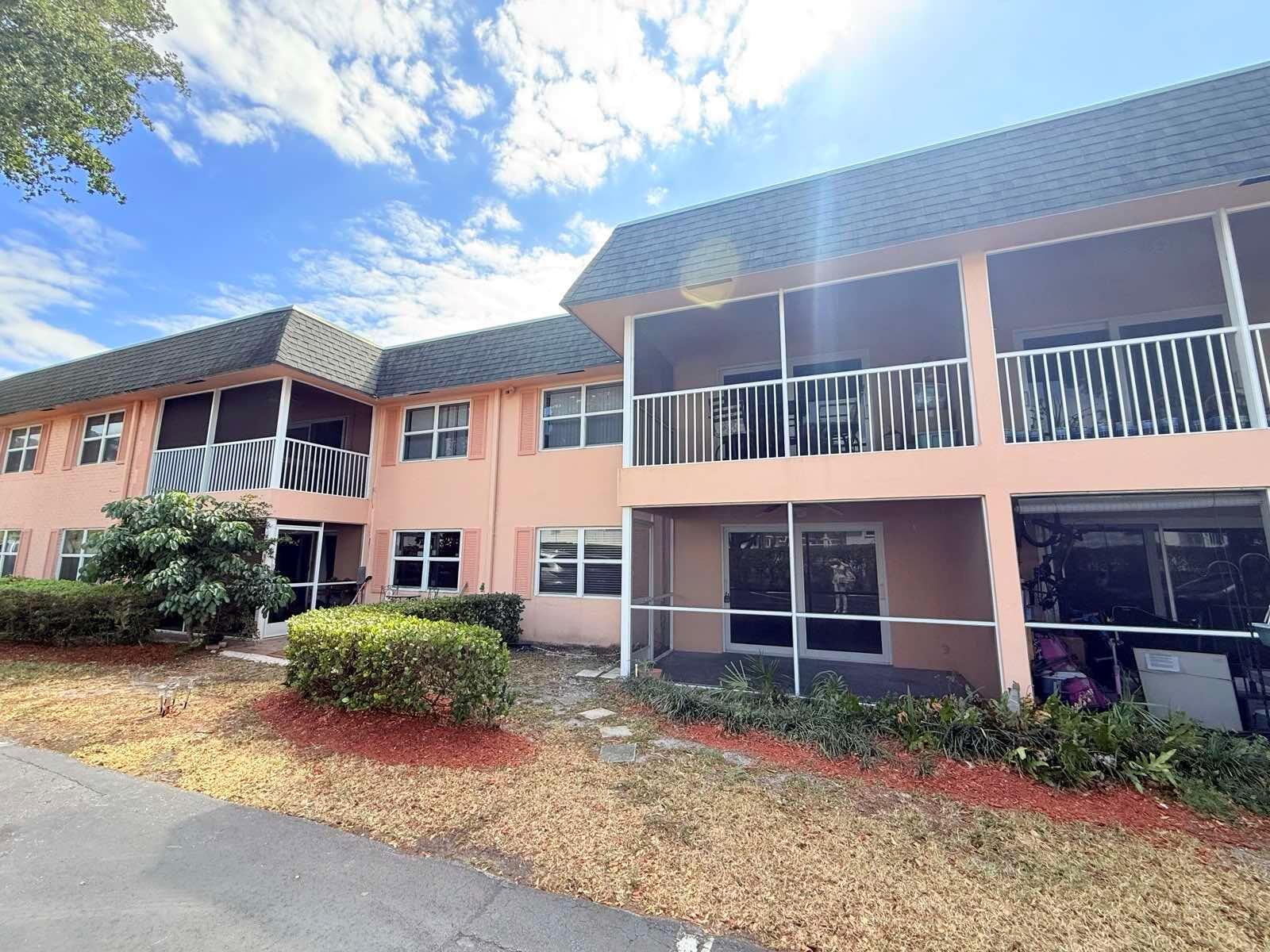 A two-story peach-colored apartment building features screened-in balconies and patios with white railings — 760 SE 2nd Avenue # D112, Deerfield Beach FL 33441, DEERFIELD BEACH, FL