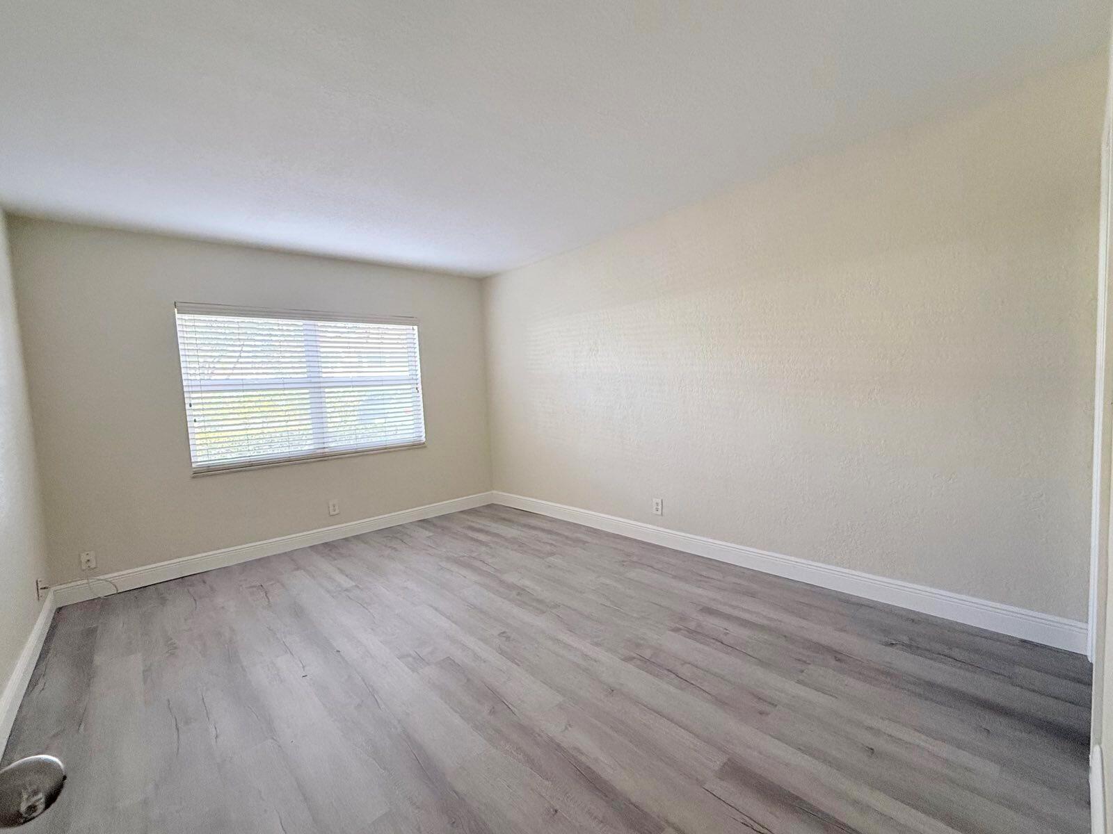 An empty room features light-colored walls, white baseboards, and gray wood-look flooring — 760 SE 2nd Avenue # D112, Deerfield Beach FL 33441, DEERFIELD BEACH, FL