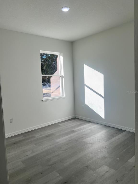 An empty room features light gray walls, wood-look flooring, a single window, and recessed lighting — 3467 W SEAHORSE LANE, CITRUS SPRINGS, FL