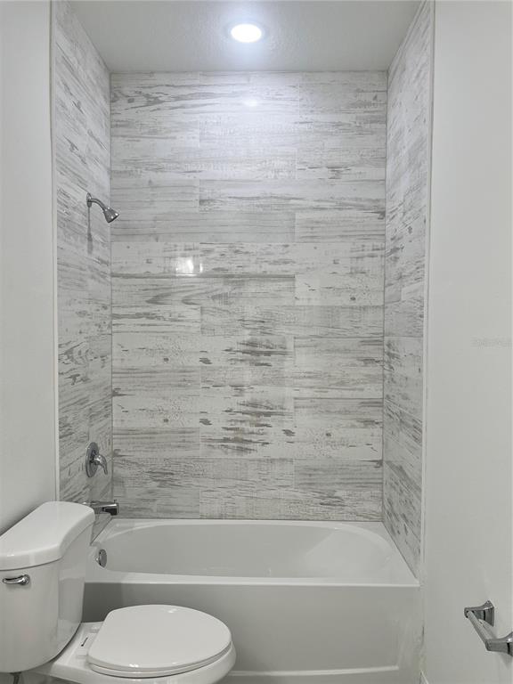 A bathroom featuring a white bathtub with light-colored, wood-look tile surround and a toilet — 3467 W SEAHORSE LANE, CITRUS SPRINGS, FL