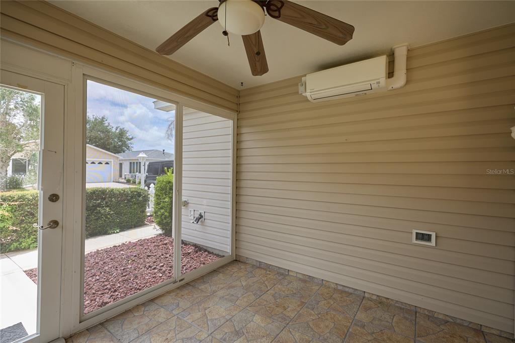 A screened-in porch features tan siding, tiled flooring, a ceiling fan, and a wall-mounted air conditioner — 2331 RILEY ROAD, THE VILLAGES, FL