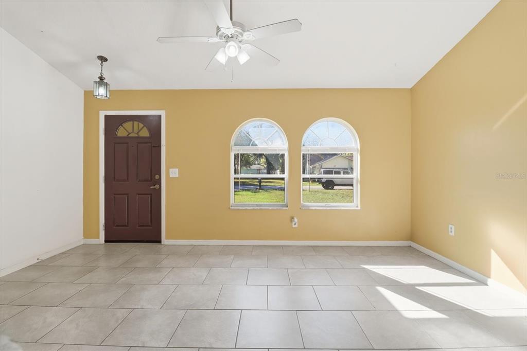 A living room with yellow walls, tile flooring, a ceiling fan, and two arched windows — 9391 W MARQUETTE LANE, CRYSTAL RIVER, FL