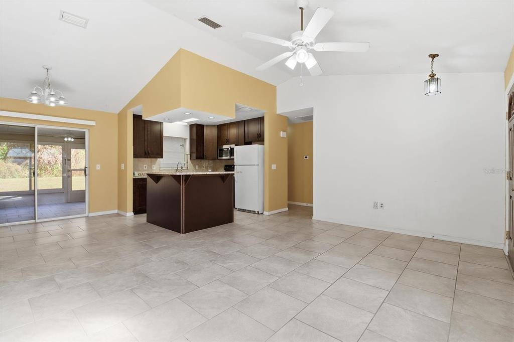 An open-concept living and dining area features tile flooring, a kitchen island, and vaulted ceilings — 9391 W MARQUETTE LANE, CRYSTAL RIVER, FL