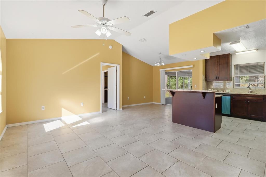 An open-concept living area features yellow walls, tile flooring, a ceiling fan, and a kitchen — 9391 W MARQUETTE LANE, CRYSTAL RIVER, FL