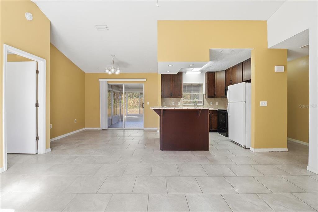 An open-concept kitchen and dining area features tile flooring, dark wood cabinets, and sliding doors — 9391 W MARQUETTE LANE, CRYSTAL RIVER, FL