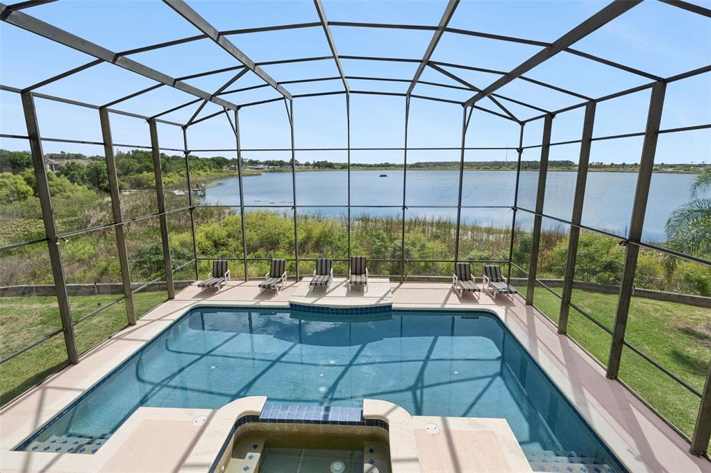 A screened-in pool and hot tub overlook a lake with a grassy shoreline — 352 CHEROKEE AVE, HAINES CITY, FL
