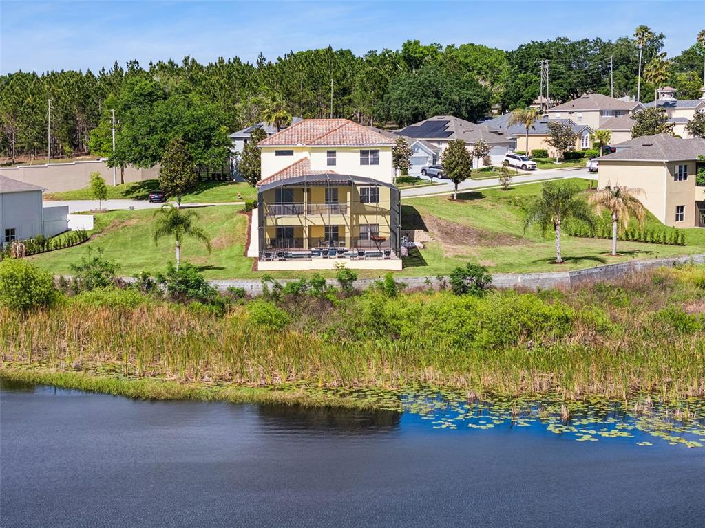 An aerial view shows a two-story house with a screened-in pool overlooking a lake — 352 CHEROKEE AVE, HAINES CITY, FL