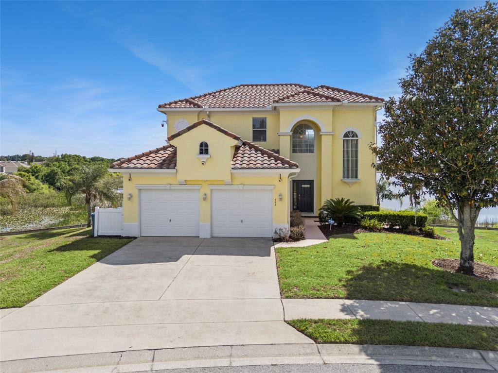 A two-story yellow house with a tile roof and a two-car garage sits on a lawn — 352 CHEROKEE AVE, HAINES CITY, FL