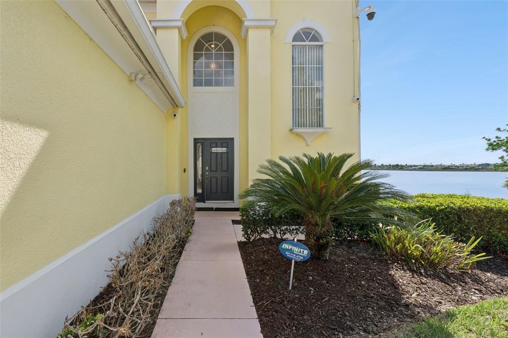 A yellow house exterior features a front walkway, a dark door, and a palm tree — 352 CHEROKEE AVE, HAINES CITY, FL