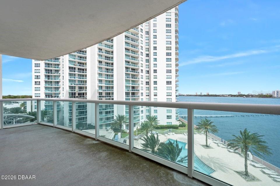 A balcony overlooks a high-rise building, a swimming pool, and a body of water — 231 RIVERSIDE DRIVE UNIT 604-1, HOLLY HILL, FL