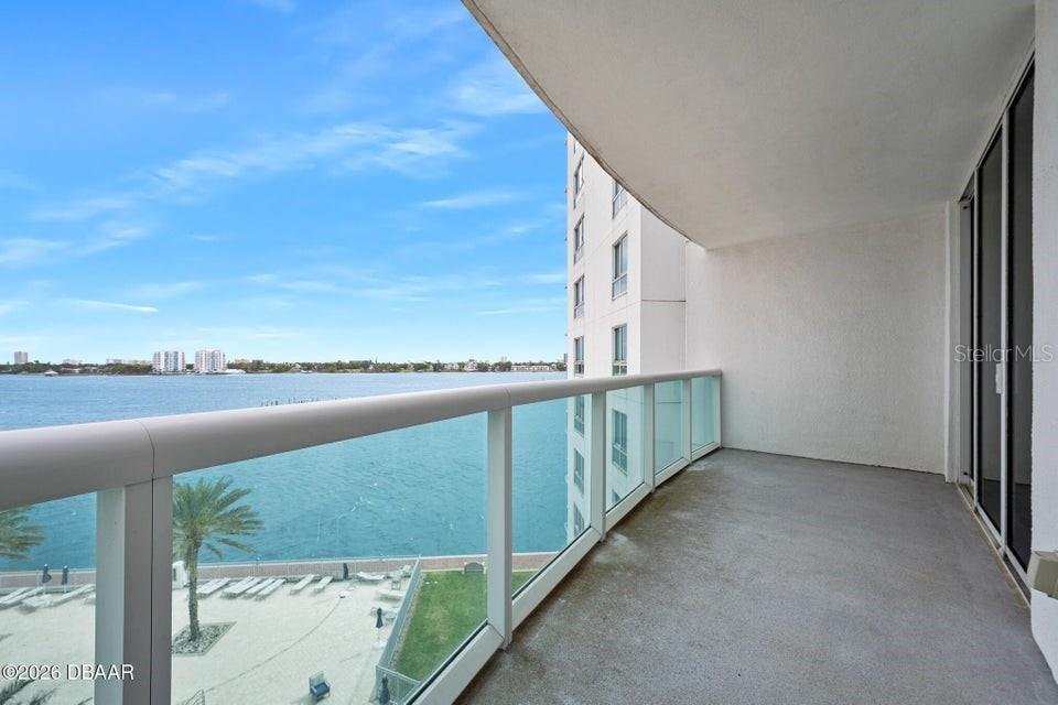 A balcony with a glass railing overlooks a body of water and a sandy beach — 231 RIVERSIDE DRIVE UNIT 604-1, HOLLY HILL, FL