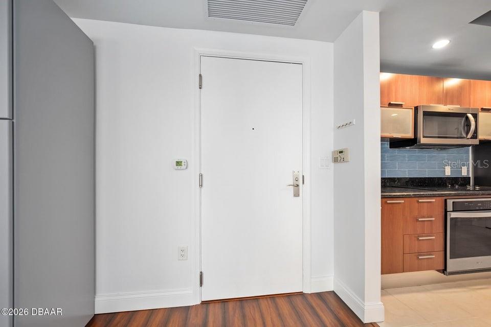 A white door stands between a gray wall and a kitchen with wood cabinets — 231 RIVERSIDE DRIVE UNIT 604-1, HOLLY HILL, FL