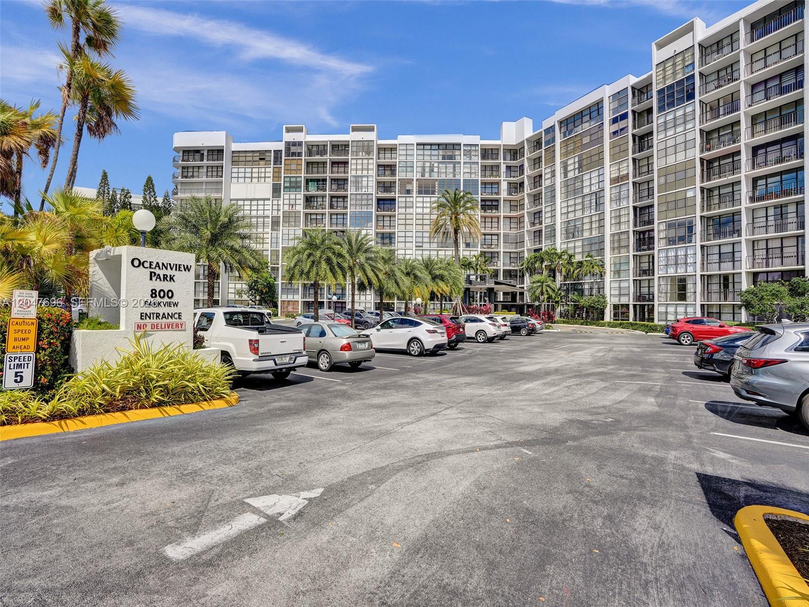 A multi-story apartment building with a parking lot and palm trees in the foreground — 800 Parkview Dr # 131, Hallandale Beach FL 33009, HALLANDALE BEACH, FL