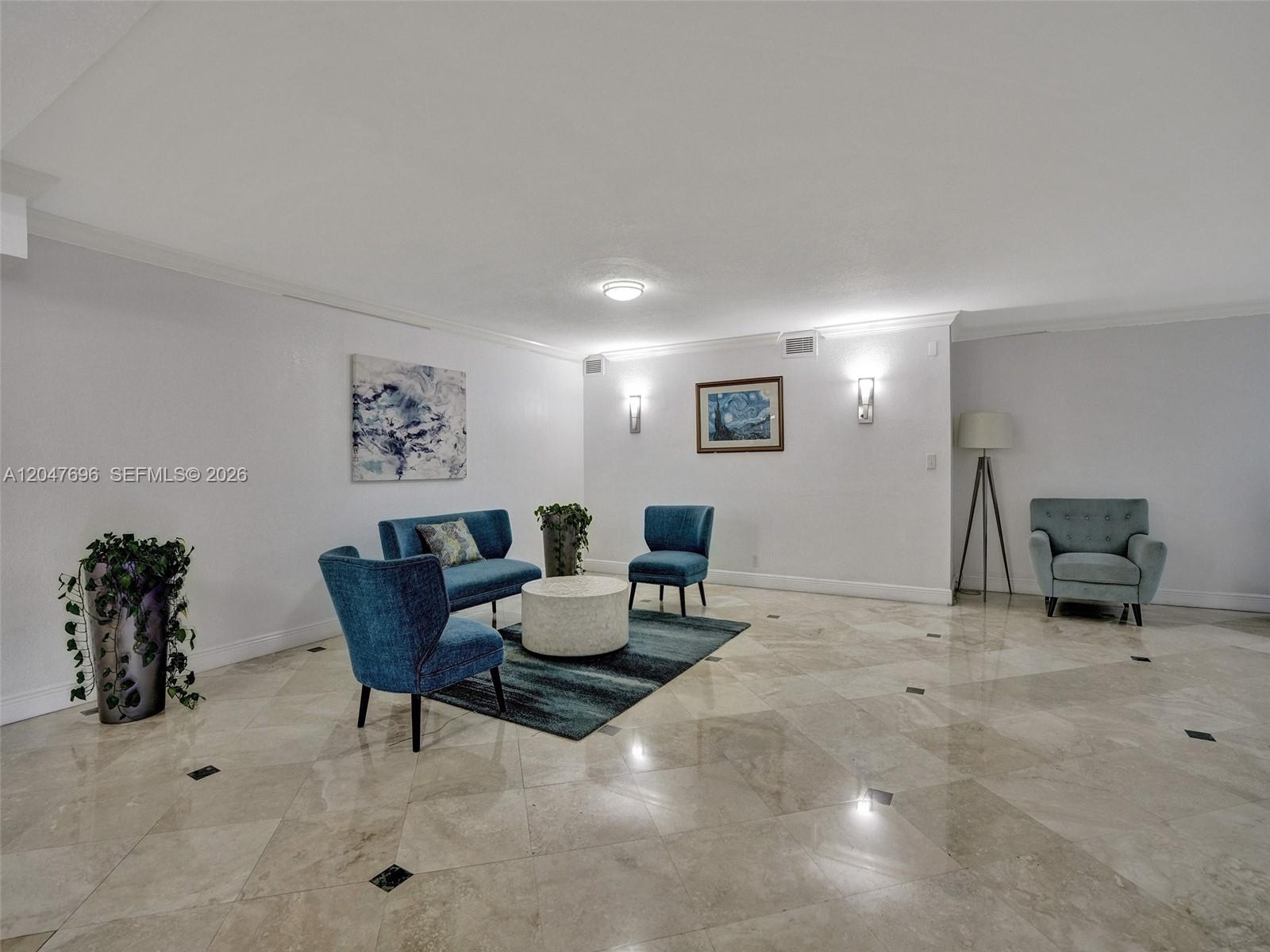 A spacious room with marble floors features a blue seating area and wall art — 800 Parkview Dr # 131, Hallandale Beach FL 33009, HALLANDALE BEACH, FL