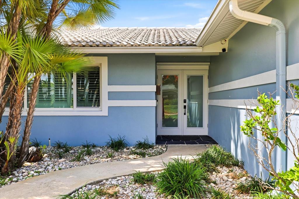 A light blue house exterior features a double glass front door and a stone walkway — 8008 13TH AVENUE S, ST PETERSBURG, FL