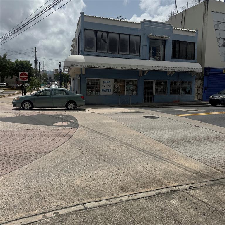 A two-story blue commercial building with a white awning stands on a street corner — AVE. COMERIO ESQ. BETANCES, BAYAMON, PR
