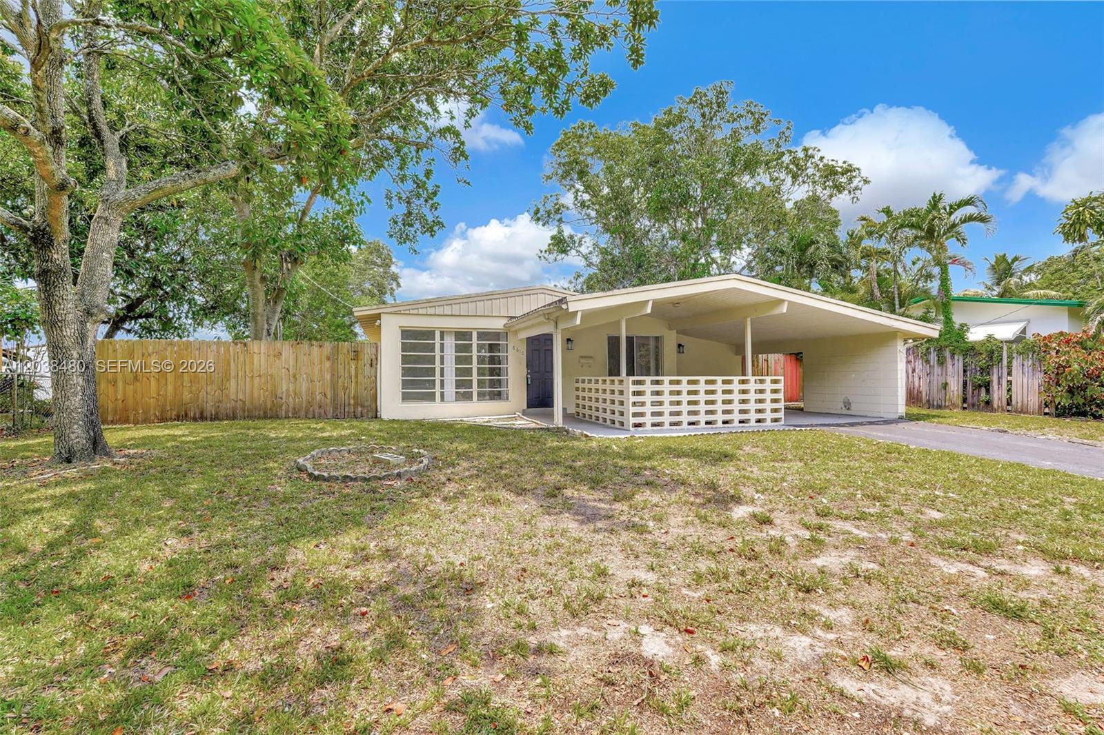 A single-story house features a carport, a decorative block wall, and a large front yard — 6610 Johnson St, Hollywood FL 33024, HOLLYWOOD, FL