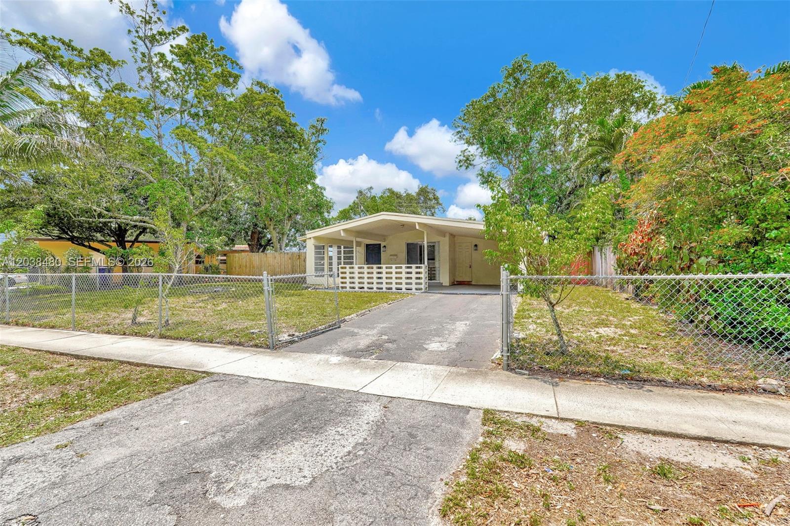 A single-story house with a carport and chain-link fence sits behind a concrete driveway — 6610 Johnson St, Hollywood FL 33024, HOLLYWOOD, FL