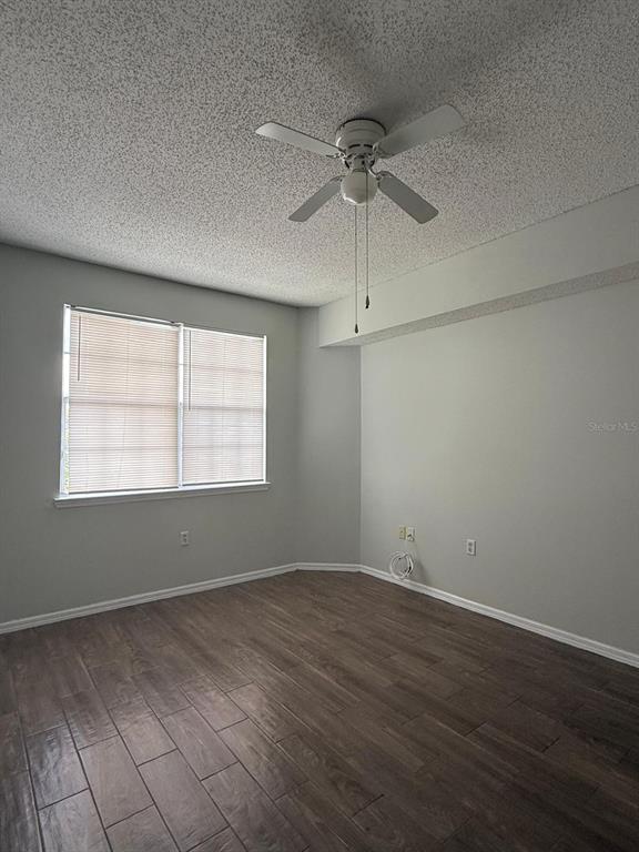 An empty bedroom features light gray walls, wood-look tile flooring, and a ceiling fan — 10831 WINDSOR WALK DRIVE UNIT 311, ORLANDO, FL