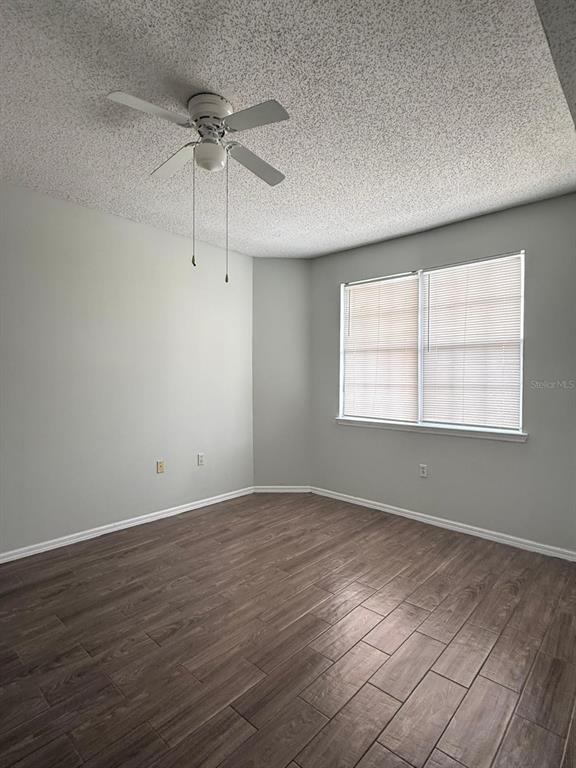 An empty bedroom features light gray walls, wood-look tile flooring, and a white ceiling fan — 10831 WINDSOR WALK DRIVE UNIT 311, ORLANDO, FL