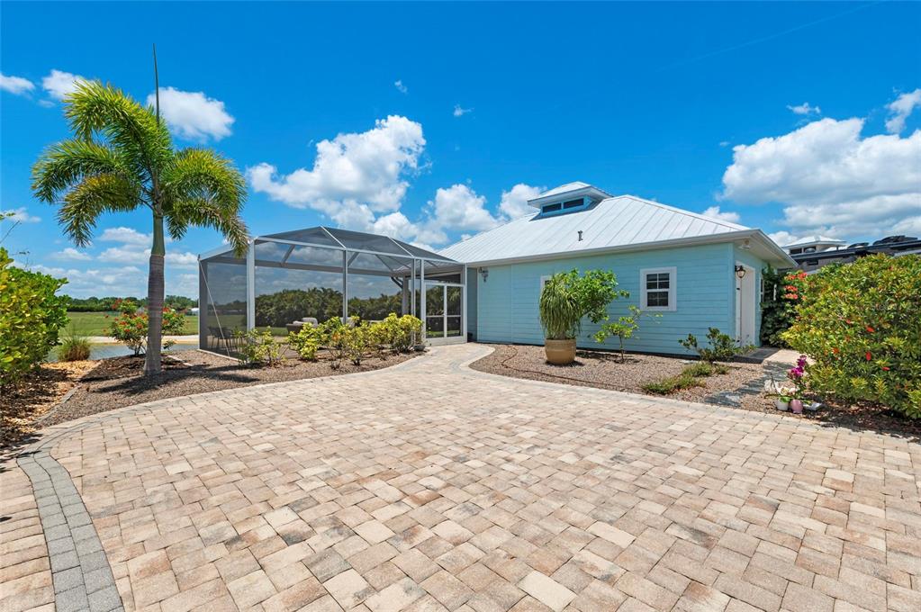 A light blue house with a metal roof, screened-in patio, and a paved stone driveway — 8196 SW SAND CRANE CIRCLE LOT 96, ARCADIA, FL