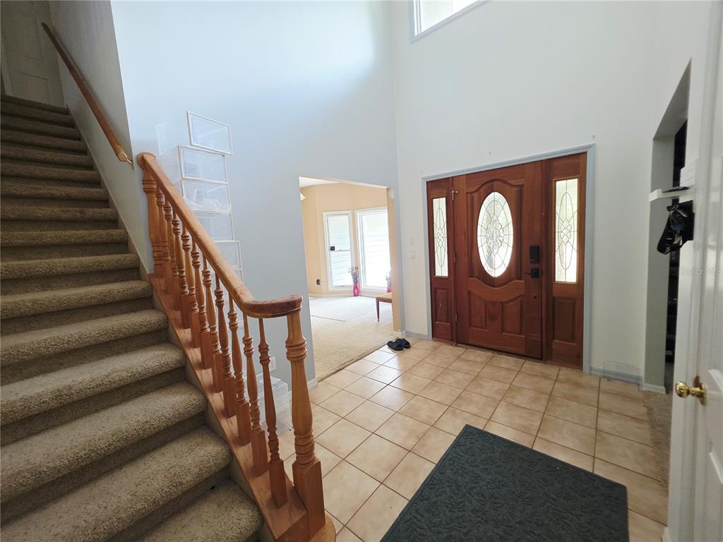 An entryway features a carpeted staircase, tile flooring, and a wooden front door with glass — 2975 E WITHLACOOCHEE TRAIL, DUNNELLON, FL