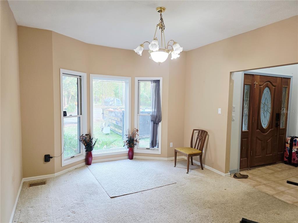 A carpeted dining area features a bay window, a chandelier, and an adjacent entryway — 2975 E WITHLACOOCHEE TRAIL, DUNNELLON, FL