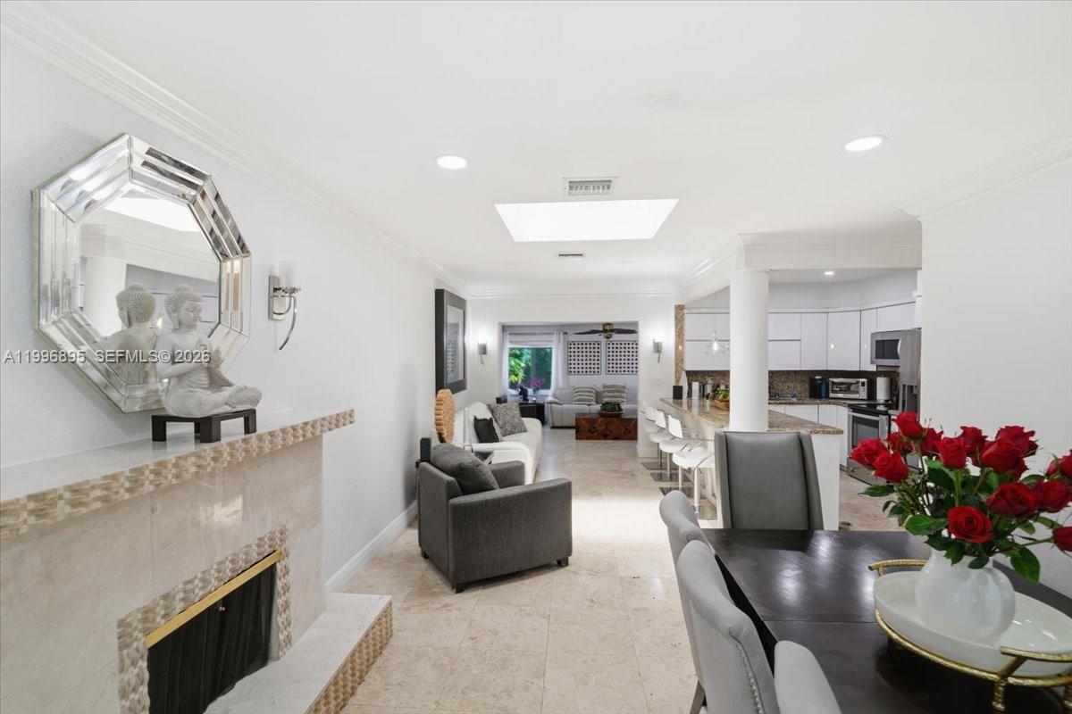 An open-concept living and dining area features a fireplace, kitchen island, and tile flooring — 6133 SW 44th Ter, Miami FL 33155, MIAMI, FL