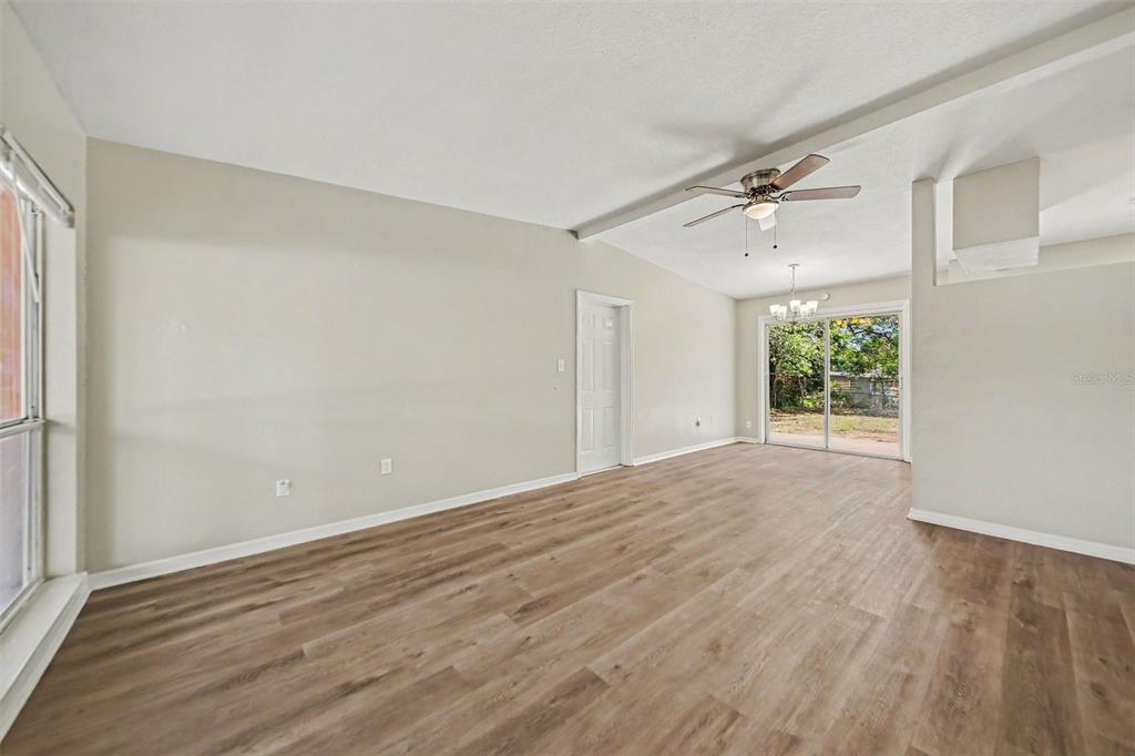 An empty living room features light-colored walls, wood-look flooring, a ceiling fan, and sliding doors — 5909 WOLF ROAD, ORLANDO, FL