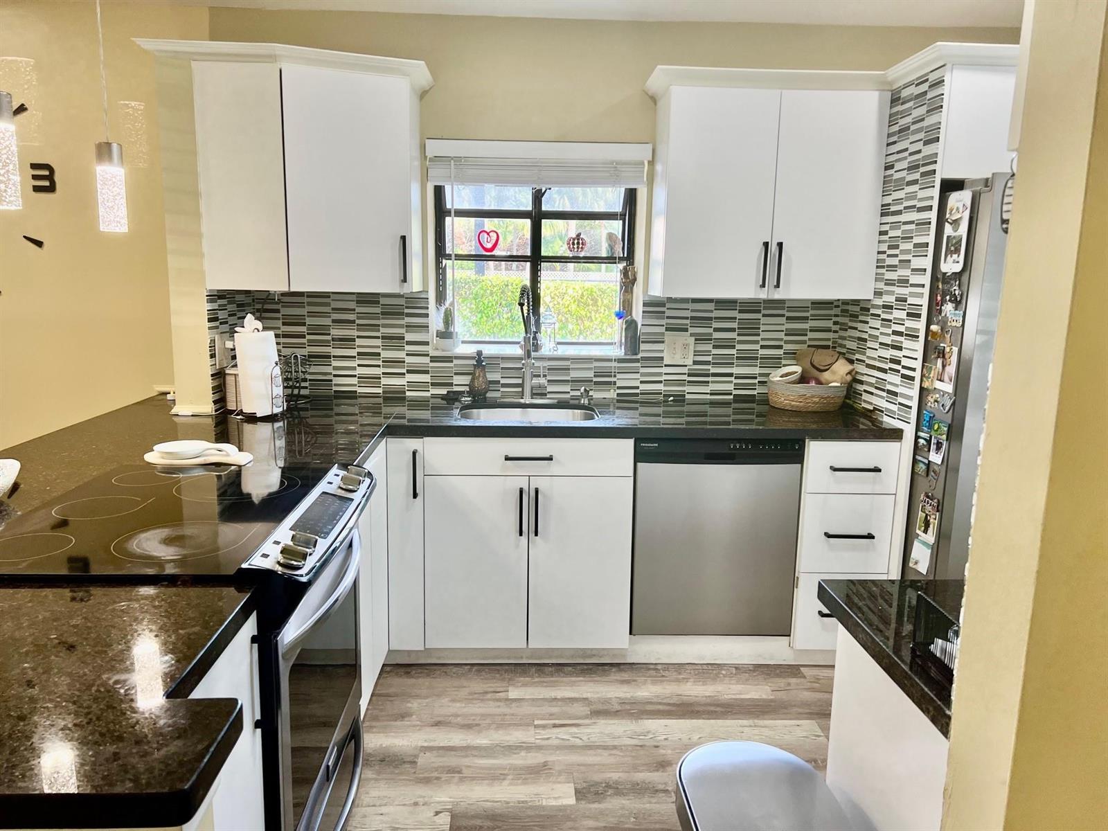 A kitchen with white cabinets, dark countertops, stainless steel appliances, and a tiled backsplash — 8053 Springtree Road # 8053, Boca Raton FL 33496, BOCA RATON, FL