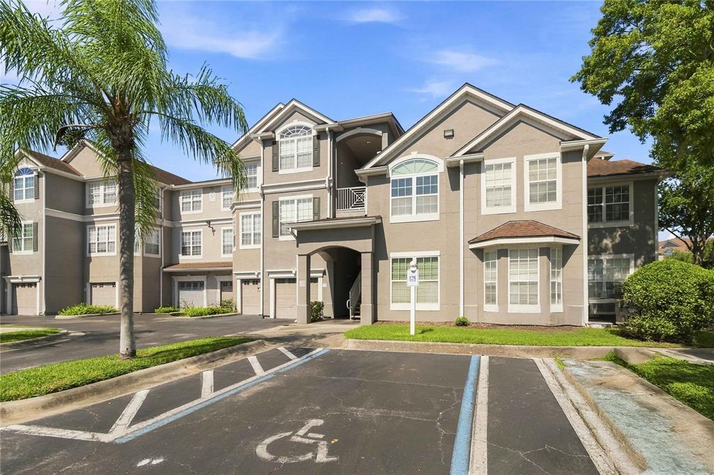 A multi-story apartment building with a parking lot featuring a designated accessible parking space — 3379 S KIRKMAN ROAD UNIT 1027, ORLANDO, FL