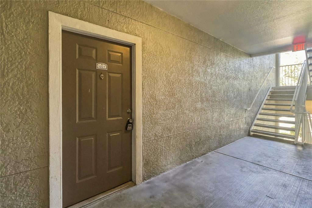 A brown apartment door labeled 1027 is located next to an outdoor staircase — 3379 S KIRKMAN ROAD UNIT 1027, ORLANDO, FL
