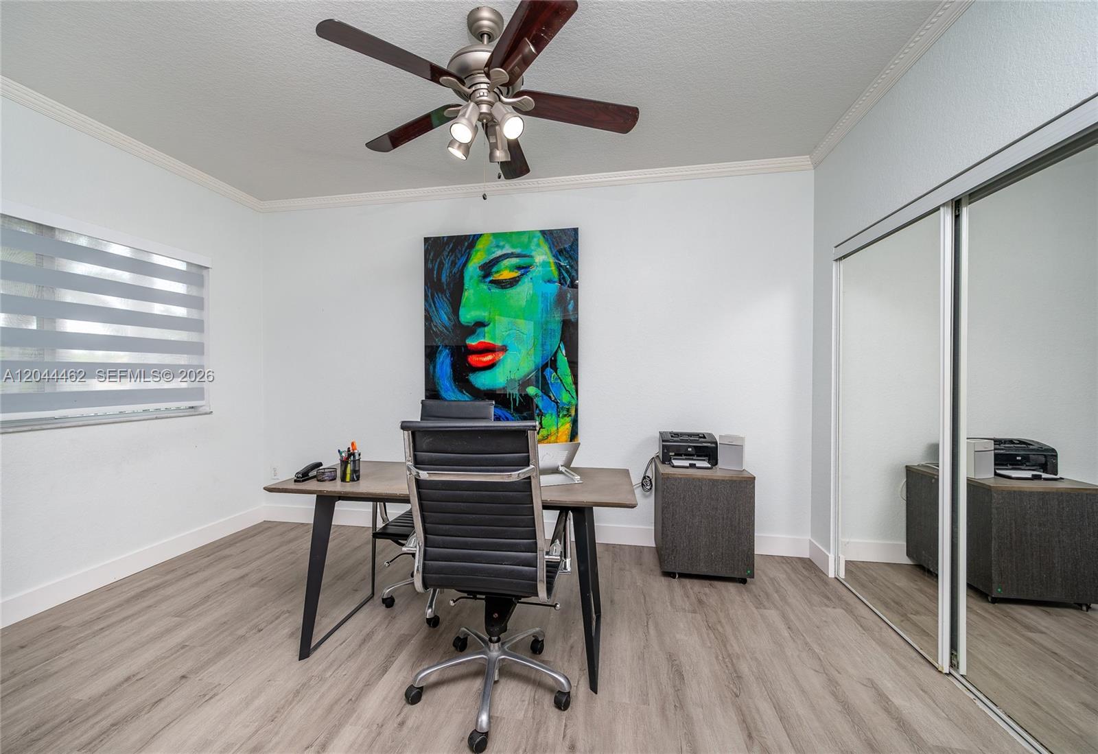 A home office features a desk, a rolling chair, a large portrait, and mirrored closet doors — 10700 NW 66th St # 204, Doral FL 33178, DORAL, FL