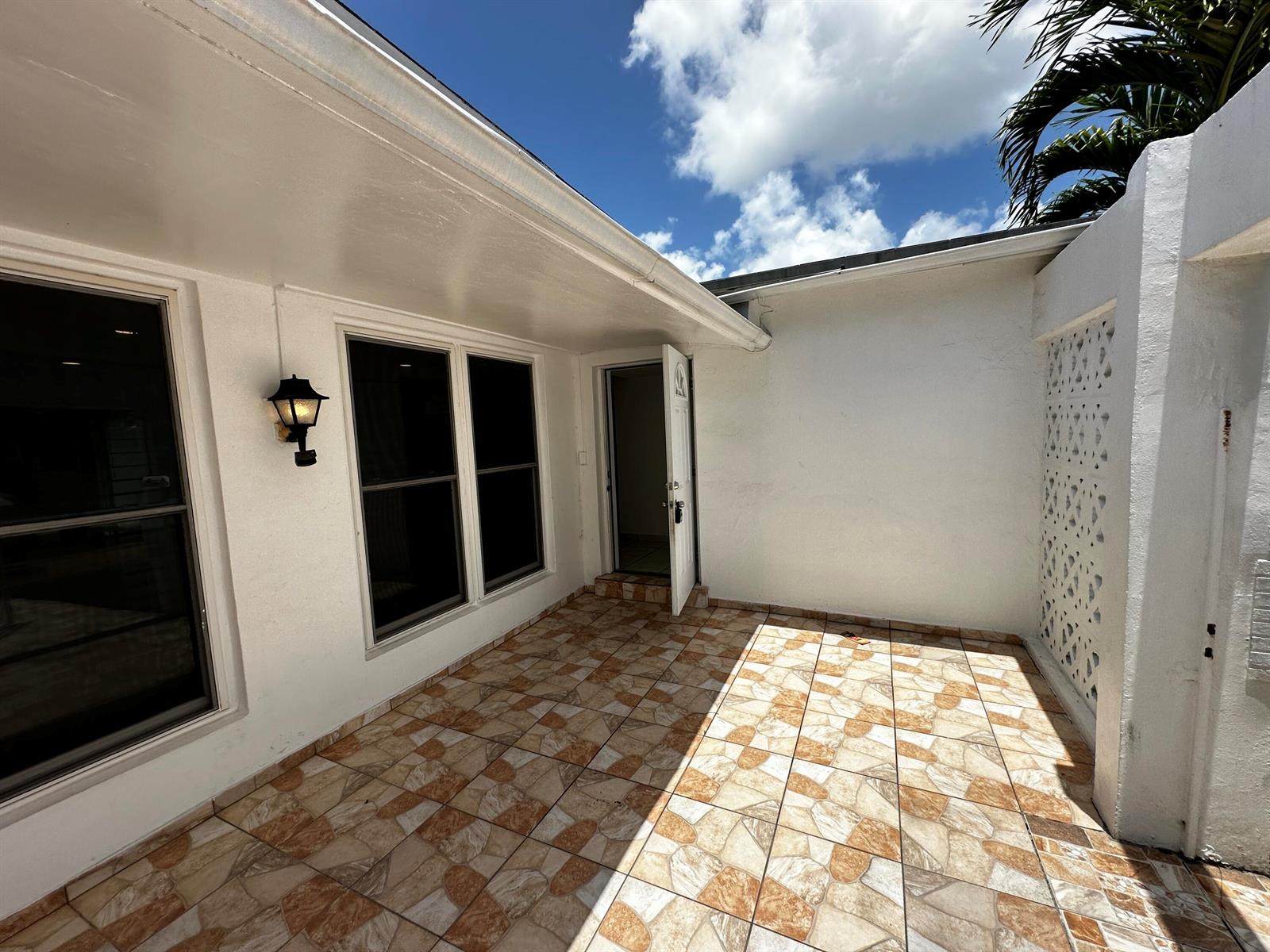 A tiled patio area features a white exterior wall, two windows, and an open doorway — 7725 Grandview Boulevard # 7725, Miramar FL 33023, MIRAMAR, FL