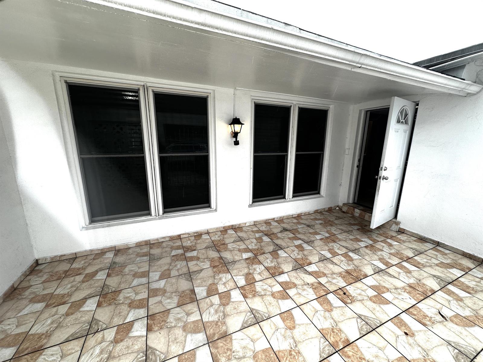 A covered patio features tiled flooring, white walls, four large windows, and an open door — 7725 Grandview Boulevard # 7725, Miramar FL 33023, MIRAMAR, FL