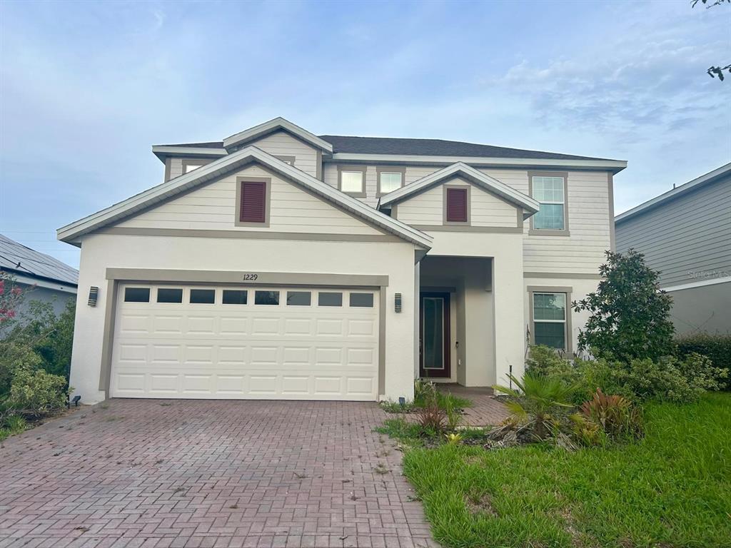A two-story house with a white stucco facade, a two-car garage, and a brick driveway — 1229 HENDON LOOP, DAVENPORT, FL