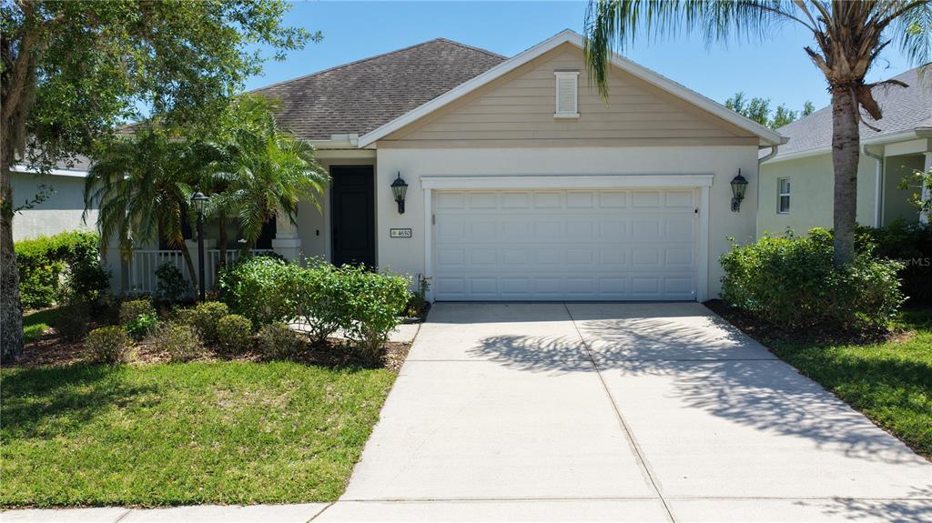 A single-story house features a white garage, a front porch, and a landscaped yard — 4650 WOODBROOK DRIVE, SARASOTA, FL