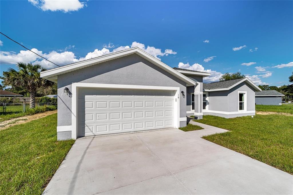 A gray single-story house with a white garage door and a concrete driveway — 15446 SW 23RD COURT ROAD, OCALA, FL