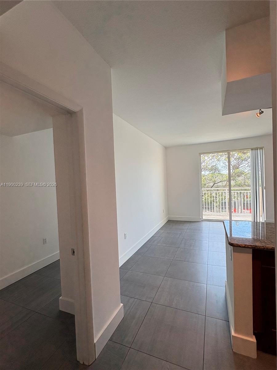 A tiled living area leads to a balcony through sliding glass doors next to a kitchen — 7275 SW 90th Way # 205, Miami FL 33156, MIAMI, FL