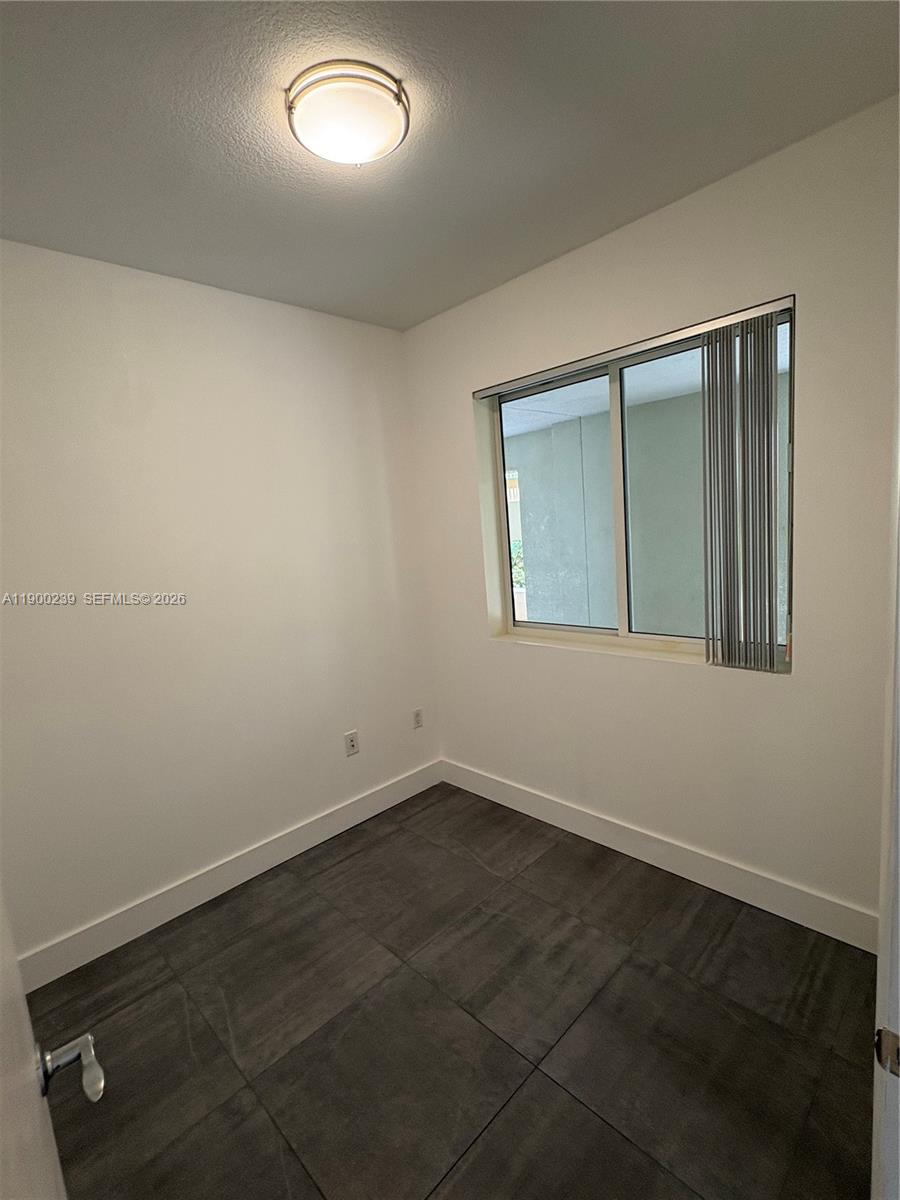 A small room features white walls, dark tile flooring, a ceiling light, and a window — 7275 SW 90th Way # 205, Miami FL 33156, MIAMI, FL