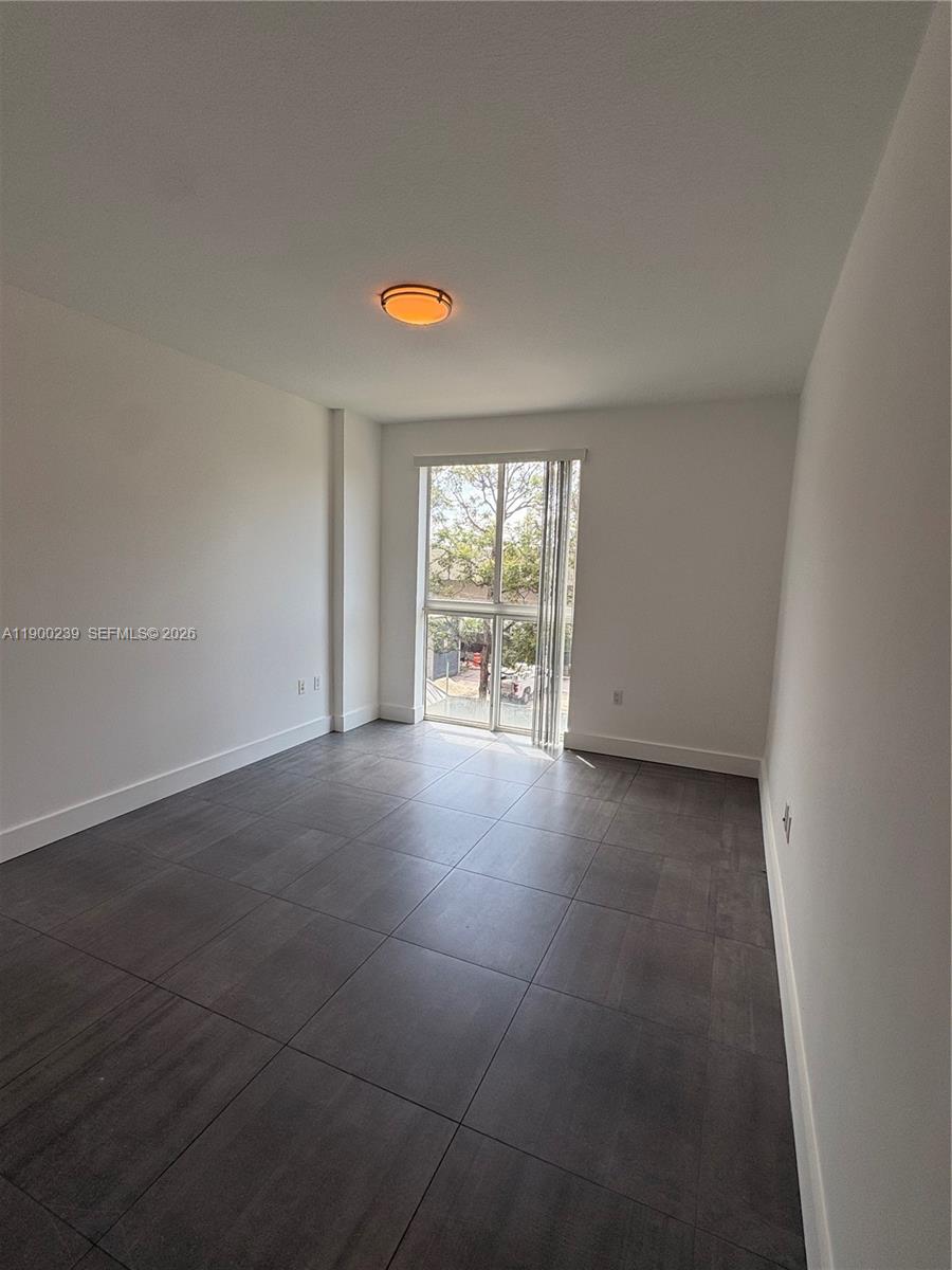 A bedroom features white walls, dark gray tile flooring, and a sliding glass door — 7275 SW 90th Way # 205, Miami FL 33156, MIAMI, FL