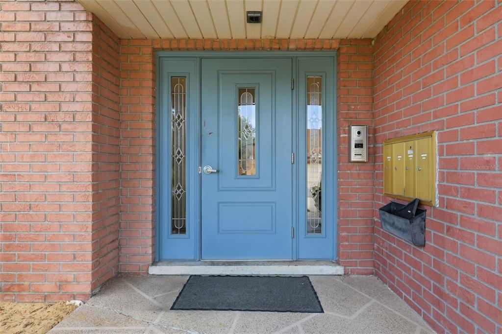 A blue front door with sidelights is set into a red brick exterior wall — 100 E OAK TERRACE DRIVE UNIT B2, LEESBURG, FL
