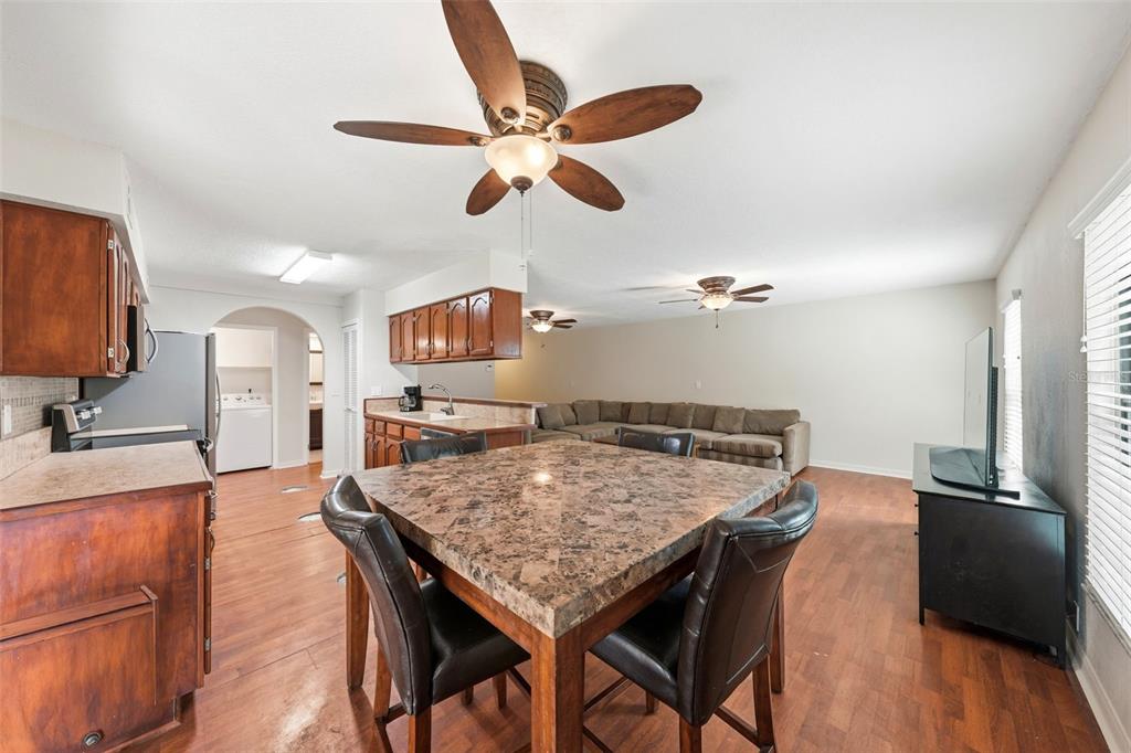 A kitchen with wood cabinets and a dining area featuring a square granite-topped table — 100 E OAK TERRACE DRIVE UNIT B2, LEESBURG, FL